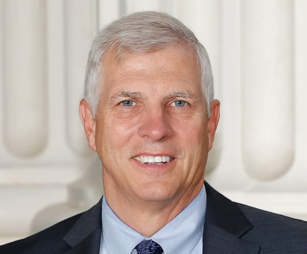 Umberg, with blue eyes and gray hair, half-smiles at the camera in a suit.