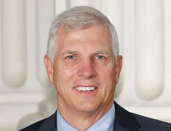 Umberg, with gray eyes and gray hair, half-smiles at the camera.